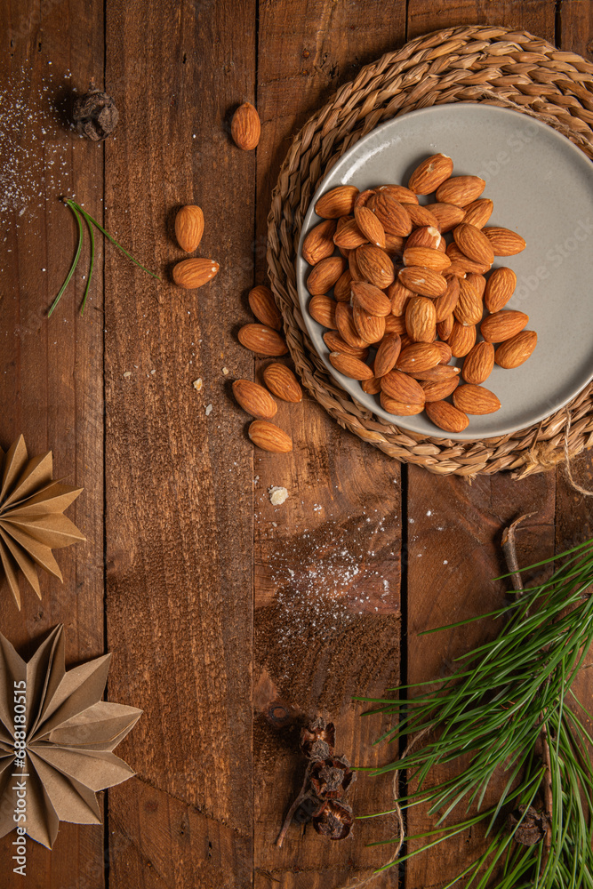 Almonds nuts on a plate placed on a rustic wooden board. Delicious sweet almonds on the wooden table, roasted almond nut for healthy food and snack Almonds nuts on a plate placed on a rustic wooden board. Delicious sweet almonds on the wooden table, roasted almond nut for healthy food and snack