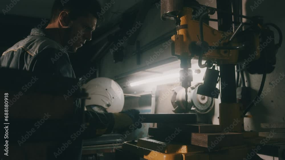 A worker works on a metal drilling machine in a workshop. Metallurgy production. A machinist operating a traditional non-CNC milling machine in a machine shop. Operates an industrial machine. 4K
