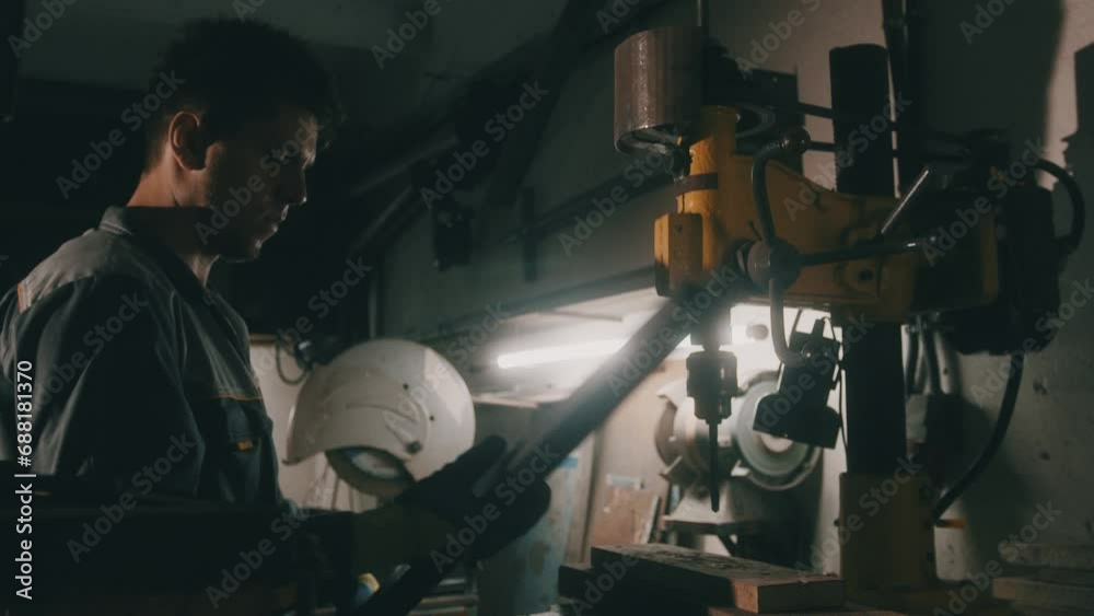 A worker works on a metal drilling machine in a workshop. Metallurgy production. A machinist operating a traditional non-CNC milling machine in a machine shop. Operates an industrial machine. 4K