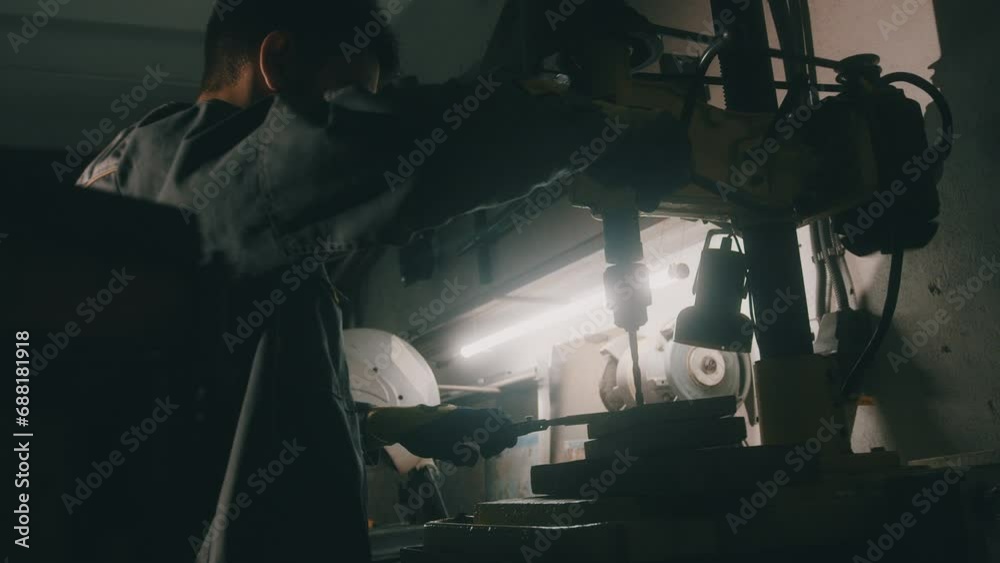 A worker works on a metal drilling machine in a workshop. Metallurgy production. A machinist operating a traditional non-CNC milling machine in a machine shop. Operates an industrial machine. 4K