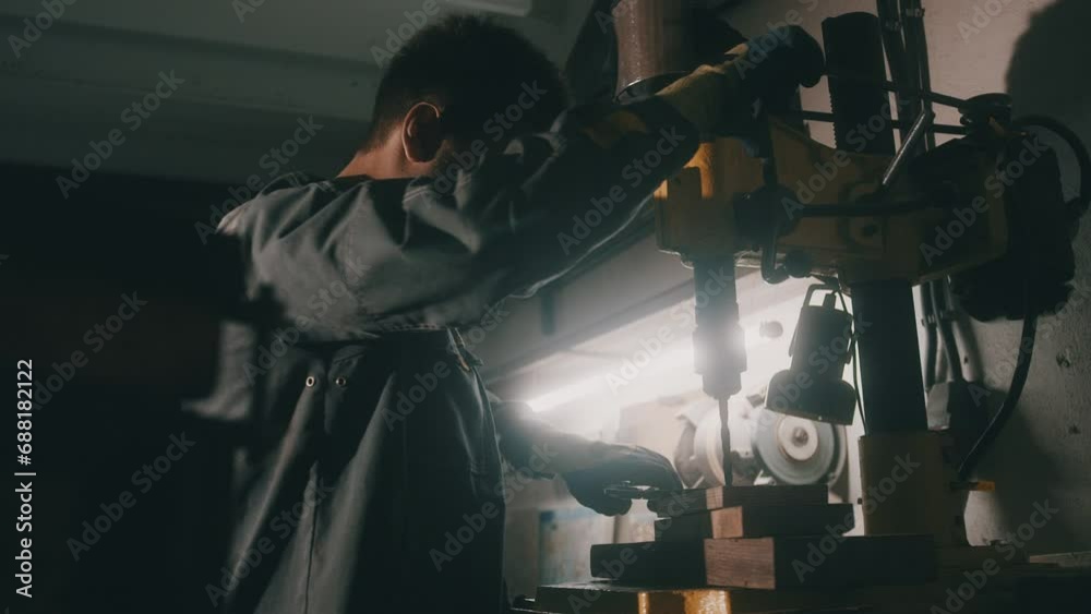 A worker works on a metal drilling machine in a workshop. Metallurgy production. A machinist operating a traditional non-CNC milling machine in a machine shop. Operates an industrial machine. 4K