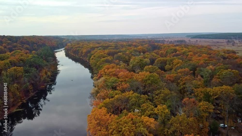 Autumn aerial speedup forward flight above river with vibrant forest on riverbanks. Cossack mountain, Koropove village on Siverskyi Donets River in Ukraine photo