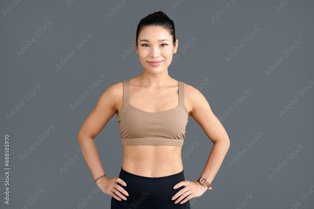 Portrait of smiling fit young woman standing against grey background Portrait of smiling fit young woman standing against grey background