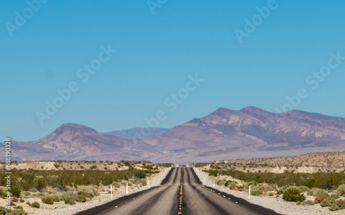 endless road in the desert, route 93, image shows a endless asphalt road in the navada desert, surrounded by untouched land and sand, with distant mountain views and rocks, taken october 2023 photo