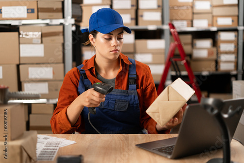 Female seller worker using scanner scanning parcel barcode tag, post shipping box, orders in dropshipping delivery service. Warehouse concept photo