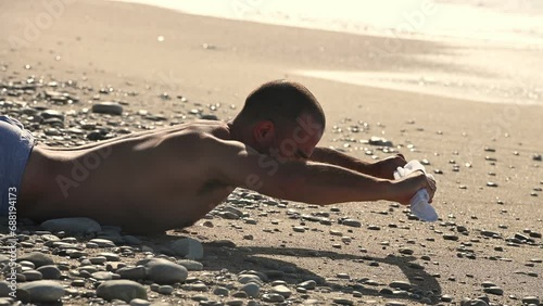 Young man doing abc exercise on the sandy beach in the morning photo