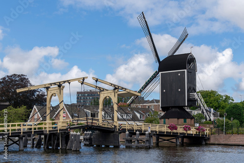 Historic windmill De Put and Rembrandt bridge in the Rijn River in the city of Leiden, the Netherlands against a white clouded blue sky photo