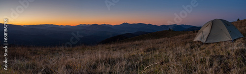 Panorama of landscape with a tourist tent. Mountain peaks Mountain range. Tourism and hiking. Panorama of sunset in the mountains.