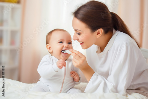 A happy mom feeds her baby from a spoon.