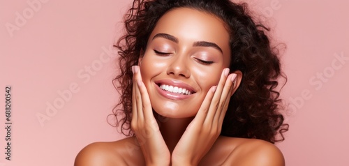 a smiling woman on pink background with hands touching her face,