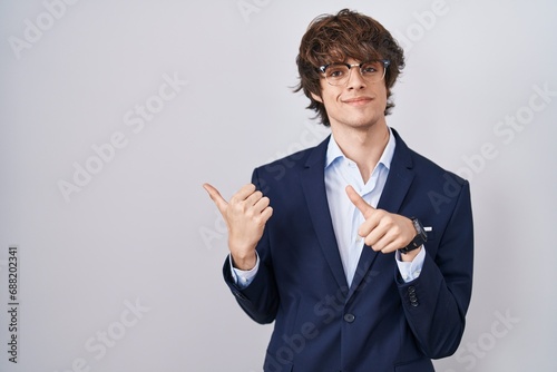 Hispanic business young man wearing glasses pointing to the back behind with hand and thumbs up, smiling confident
