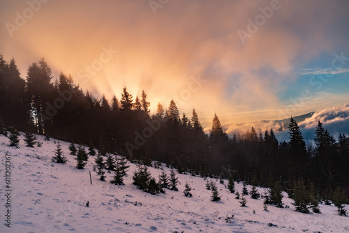 Sunset in the winter mountains. Rays of the sun from behind the winter mountains. Beautiful winter landscape. © vzwer