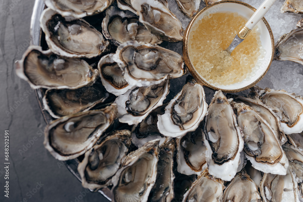 Close-up of fresh open oysters with sauce on round platter in restaurant. Seafood. Healthy Close-up of fresh open oysters with sauce on round platter in restaurant. Seafood. Healthy