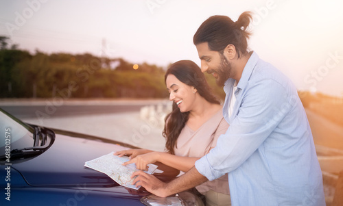 Middle eastern couple planning route with map on car