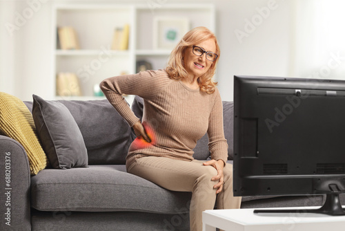 Mature woman with pain in the lower side back sitting on a sofa photo