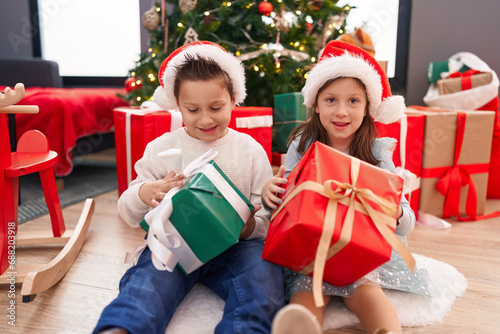 Adorable boy and girl smiling confident holding christmas gift at home