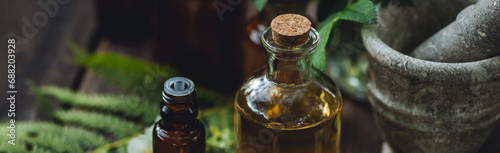 Concept of alternative herbal medicine. Bottles of tincture or potion, organic essential oils, healthy herbs, floral extracts on wooden table. Pure natural ingredients for cosmetic production banner photo