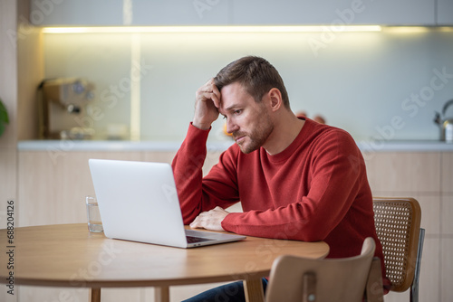 Disappointed hopeless unemployed middle aged man jobseeker sitting at table, reading advertisements on web sites, looking through vacancies, hunting for job. Depressed man after dismissal, job cut photo