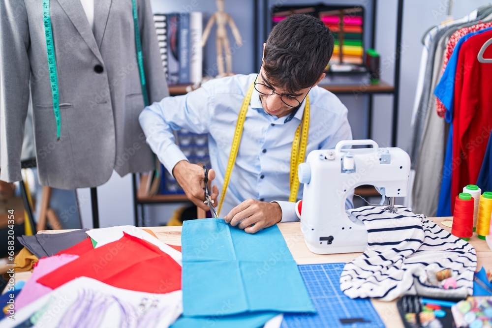 Young hispanic man tailor smiling confident cutting cloth at tailor shop Young hispanic man tailor smiling confident cutting cloth at tailor shop