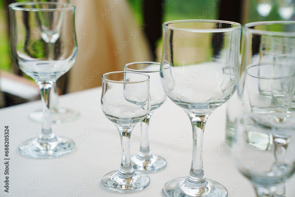 Empty wine glasses and shot glasses on a table with a white tablecloth. Empty wine glasses and shot glasses on a table with a white tablecloth.