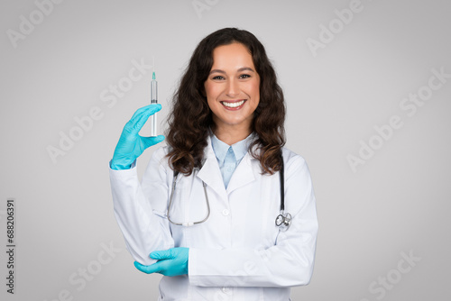 Cheerful caucasian woman doctor wearing sterile gloves  holding medical syringe  prepared for an injection