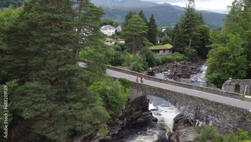 Aerial view of couple taking a selfie on bridge over waterfall in Killin, United Kingdom.  photo