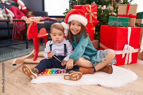 Adorable boy and girl playing xylophone celebrating christmas at home