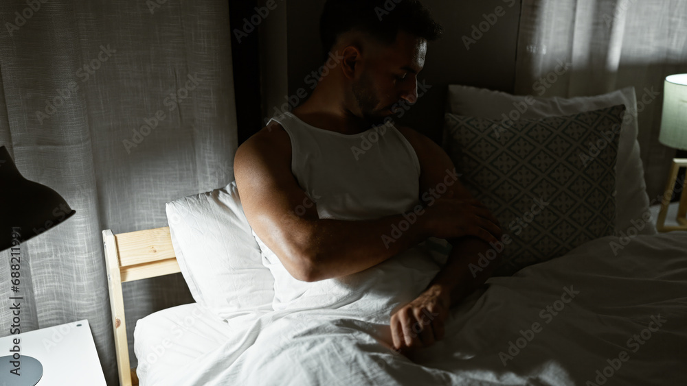Young arab man sitting on bed scratching arm for itchy at bedroom