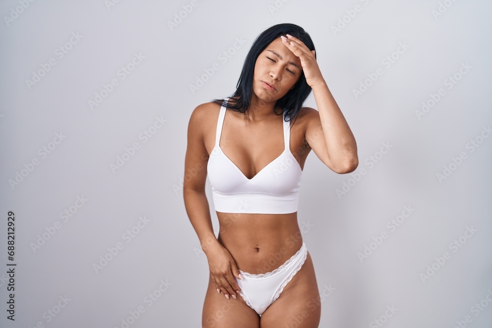 Hispanic woman wearing lingerie worried and stressed about a problem with hand on forehead, nervous and anxious for crisis
