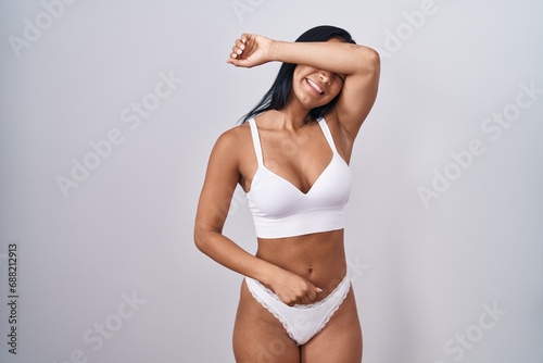 Hispanic woman wearing lingerie covering eyes with arm smiling cheerful and funny. blind concept.