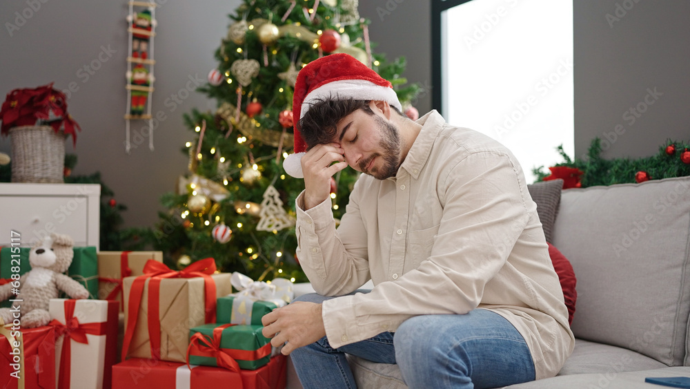 Young hispanic man celebrating christmas stressed at home