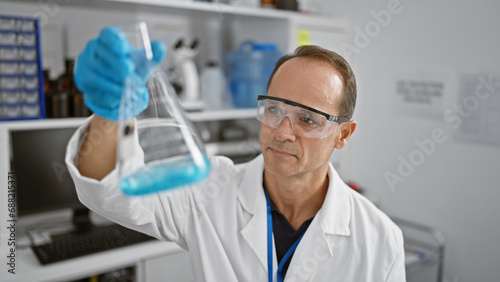 Handsome middle-aged man  a devoted scientist  meticulously measuring liquid in a test tube at his professional lab  epitome of safety and concentration