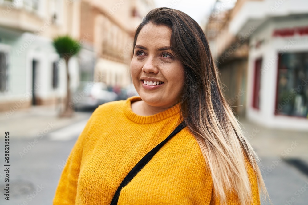 Young beautiful plus size woman smiling confident looking to the side at street