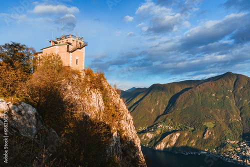 Wide-angle sunset view from the summit of Monte San Salvatore overlooking Lake Lugano Breathtaking panorama of the city, Melide causeway and the Swiss Alps in Ticino, Switzerland - November 2023