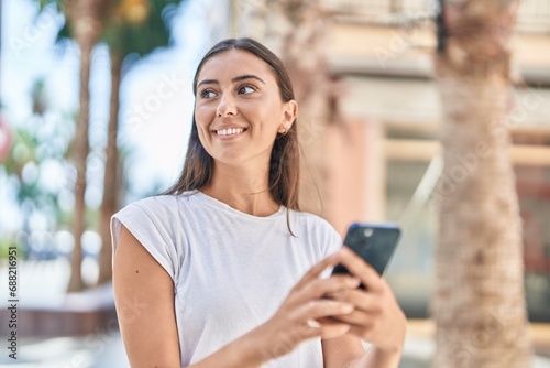 Young beautiful hispanic woman smiling confident using smartphone at street