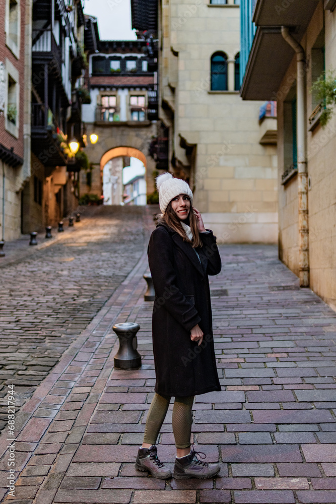Tourist braves winter evening, strolling through Christmas-lit Hondarribia streets. Tourist braves winter evening, strolling through Christmas-lit Hondarribia streets.