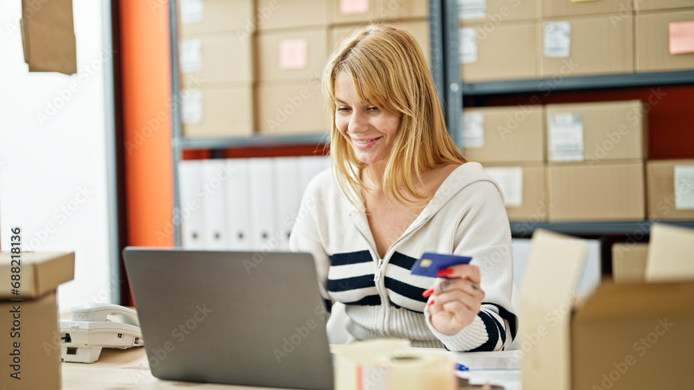 Young blonde woman ecommerce business worker shopping with laptop and credit card at office