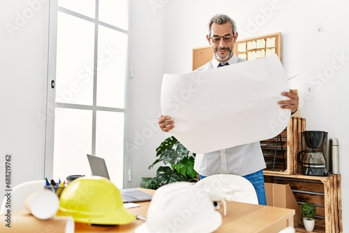 Middle age grey-haired man architect looking house plans at office