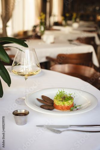 Tartare with salmon, avocado, microgreens and crouton on a large white plate.