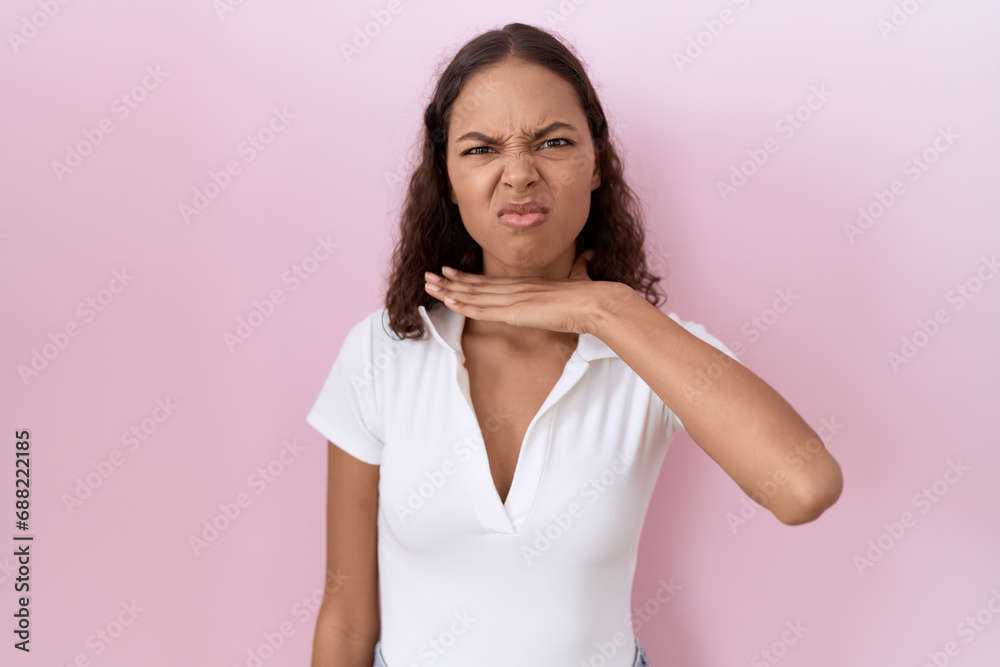 Young hispanic woman wearing casual white t shirt cutting throat with hand as knife, threaten aggression with furious violence Young hispanic woman wearing casual white t shirt cutting throat with hand as knife, threaten aggression with furious violence