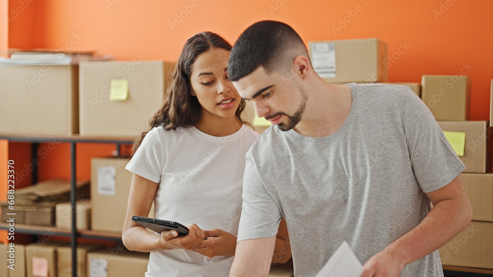 Together in business, two serious workers, a man and woman, concentrate on reading a document on a laptop at the office Together in business, two serious workers, a man and woman, concentrate on reading a document on a laptop at the office