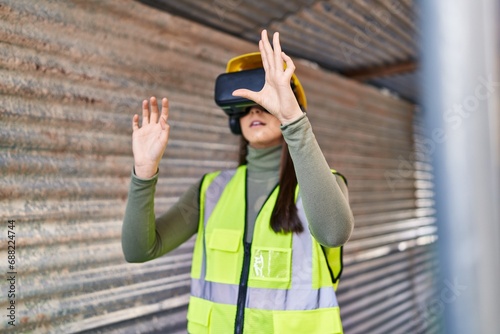 Young beautiful hispanic woman architect using virtual reality glasses at street