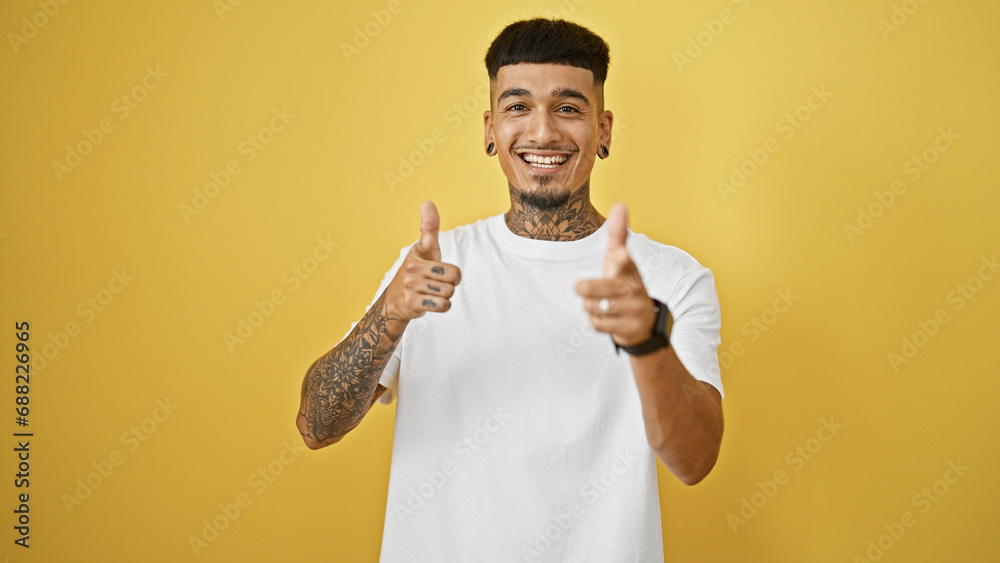Cheerful young latin man, oozing confidence, pointing fingers at you through the camera! isolated on a yellow background for pure joy. Cheerful young latin man, oozing confidence, pointing fingers at you through the camera! isolated on a yellow background for pure joy.