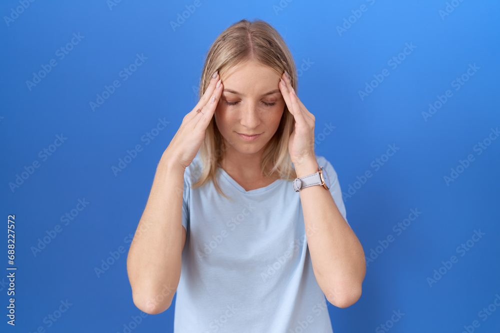 Fototapeta premium Young caucasian woman wearing casual blue t shirt with hand on head, headache because stress. suffering migraine.