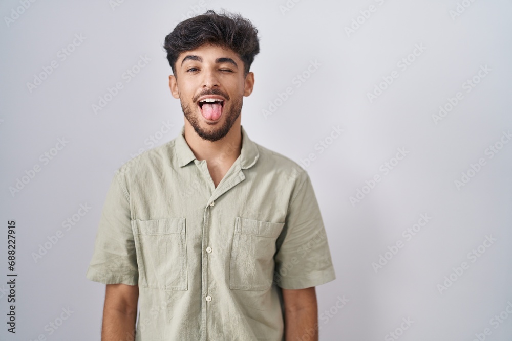 Arab man with beard standing over white background sticking tongue out happy with funny expression. emotion concept. Arab man with beard standing over white background sticking tongue out happy with funny expression. emotion concept.