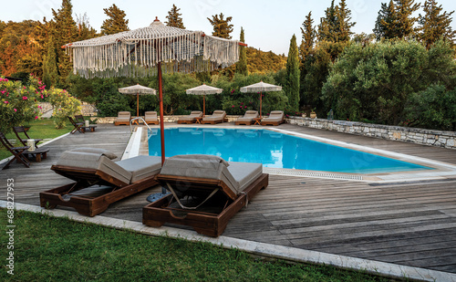 Swimming pool and beds for relaxing in summer. Swimming pool in the nature among greenery.