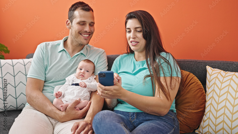 Family of three using smartphone sitting on the sofa at home Family of three using smartphone sitting on the sofa at home