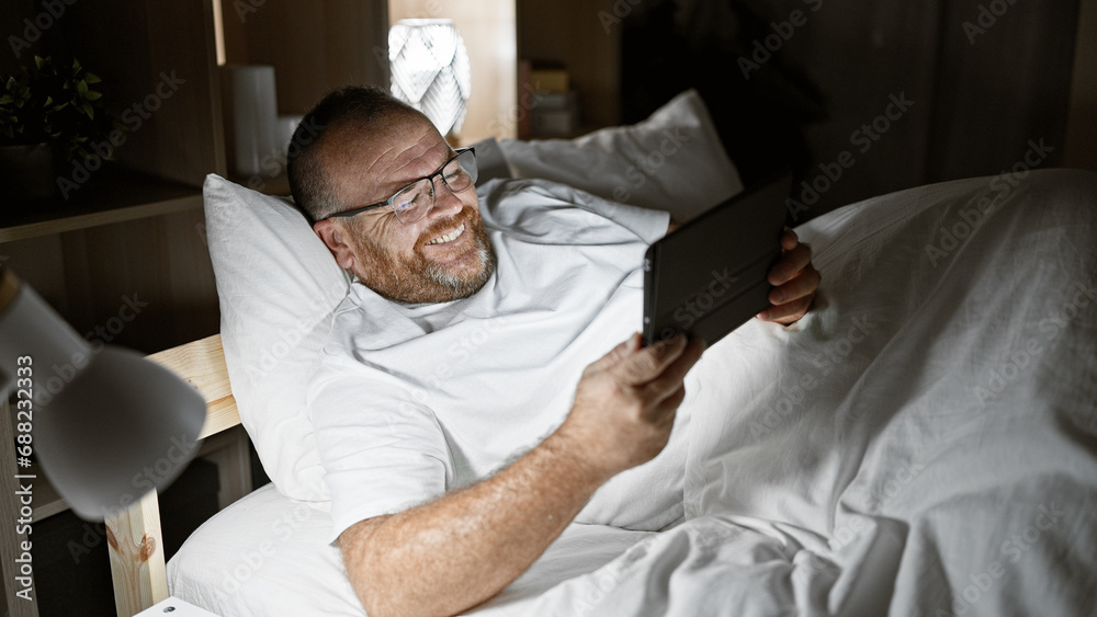Caucasian man watching video on touchpad lying on bed at bedroom Caucasian man watching video on touchpad lying on bed at bedroom
