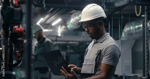 Wallpaper Mural Professional African American inspector checks piping system on modern factory. Multiethnic team of technician specialists work on plant using laptop and tablet computers. Concept of heavy industry. Torontodigital.ca