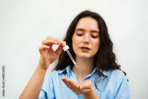 Girl is holding pipette with hyaluronic serum or acid in hands. Young woman with acid dropper in hands.